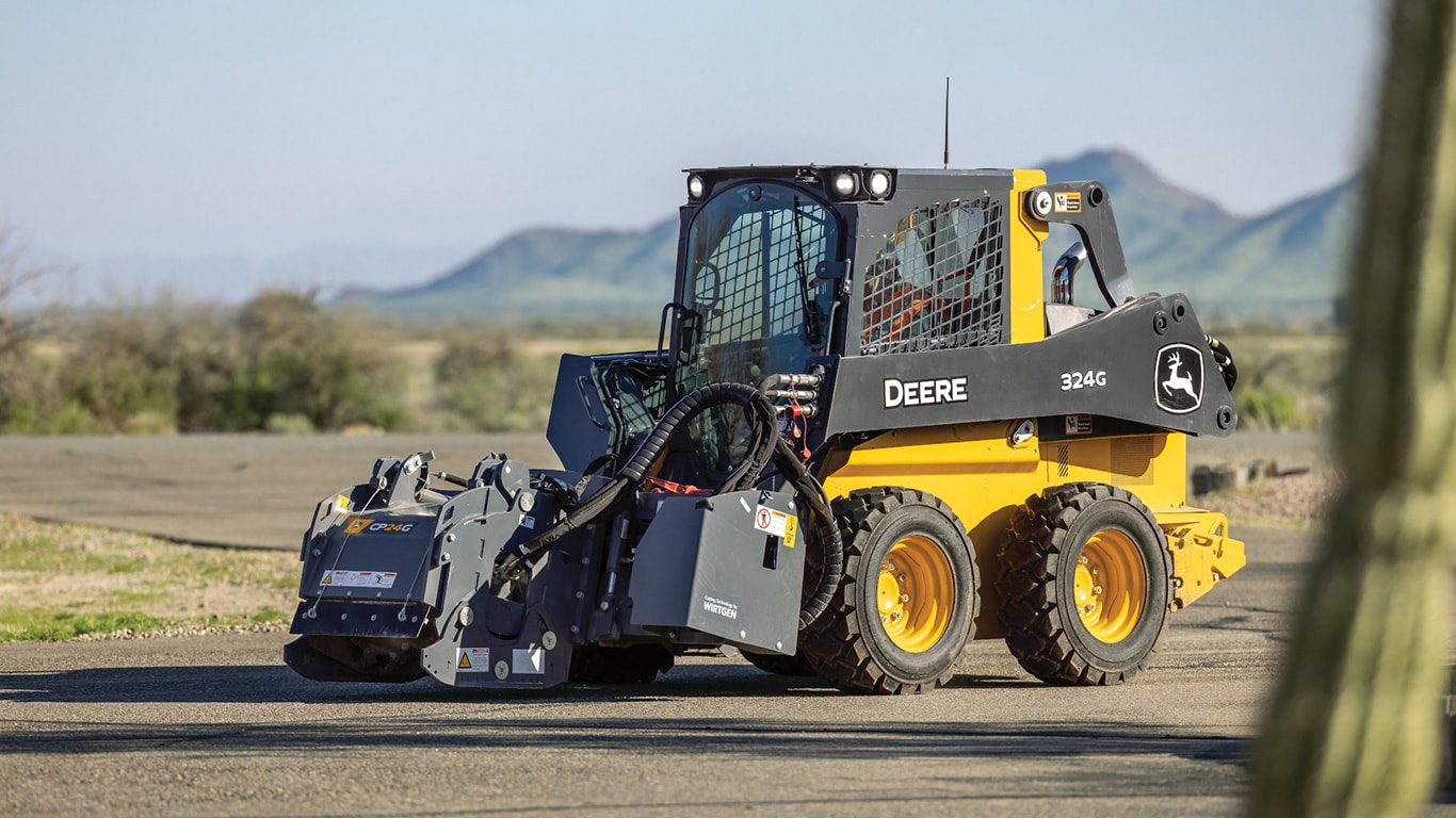 John Deere 324g skid steer loader showcasing its maneuverability on uneven pavement in an arid environment.